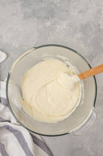 istock Dough for making a vanilla cake with blueberries in a bowl on a gray concrete background. Recipe step by step. Top view. 1301192578