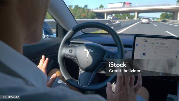 Close Up Unrecognizable Man Tentatively Lets Go Of The Steering Wheel Of A Tesla Stock Photo - Download Image Now