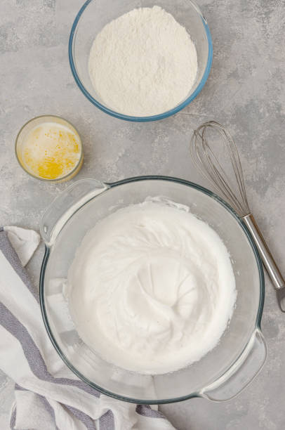 istock Whipped egg whites with sugar in a bowl on a gray concrete background. Cooking a vanilla cake with blueberries. Recipe step by step. Top view. 1301192728