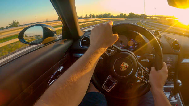 pov: colpo in prima persona di crociera lungo l'autostrada in una porsche al tramonto. - porsche foto e immagini stock