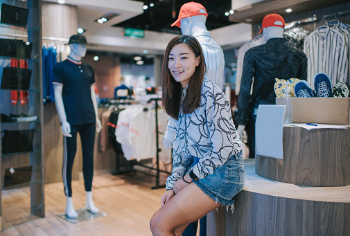 asian chinese menswear retail store female owner looking at camera in front of her business retail