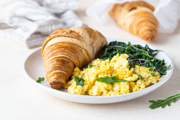 istock Croissant served with scrambled eggs and spinach on plate, light concrete background. Breakfast. 1301198281