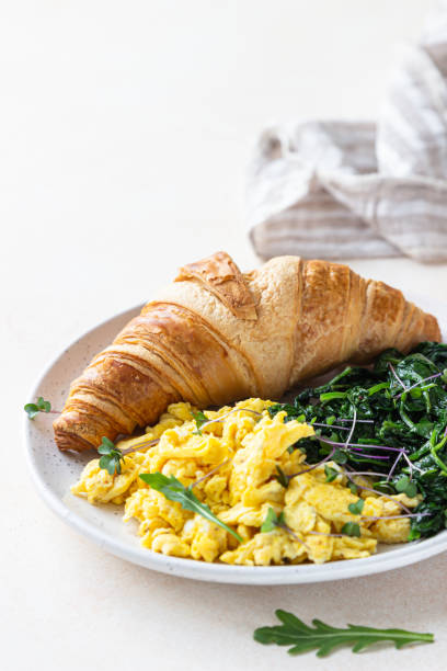 istock Croissant served with scrambled eggs and spinach on plate, light concrete background. Breakfast. 1301198358