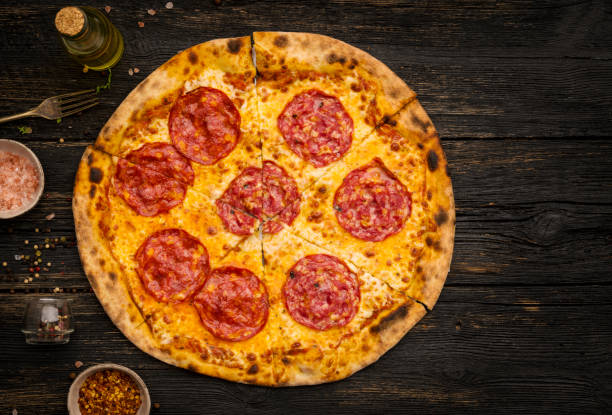 istock Pepperoni pizza on a dark wooden table 1301198367