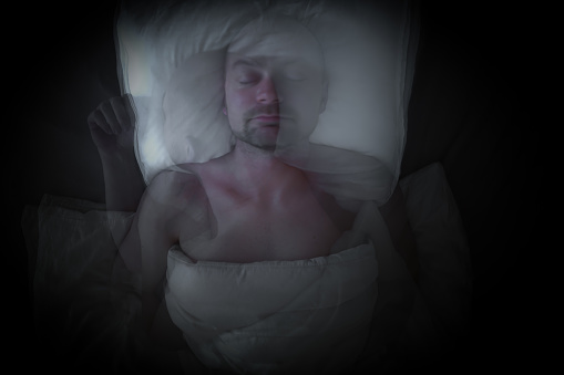 Man having bad dreams and moves his head. Time lapse photo with abstract motion blur.
