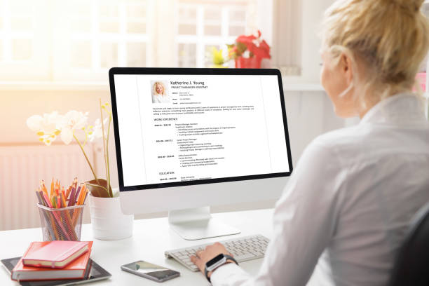 Woman creating her CV on computer. All contents in document are made up. Woman working on CV on computer. All contents in document are made up. good cv stock pictures, royalty-free photos & images