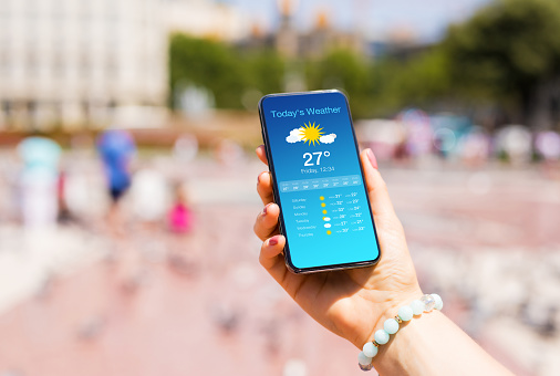 Woman outdoors in city checking weather forecast on her mobile phone