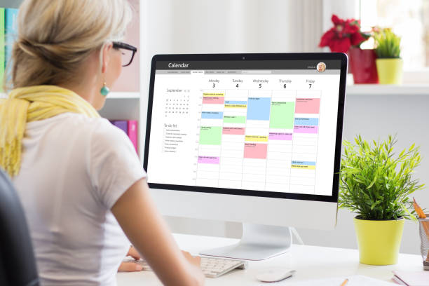 mujer usando aplicación de calendario en computadora en la oficina - monitor de ordenador fotos fotografías e imágenes de stock