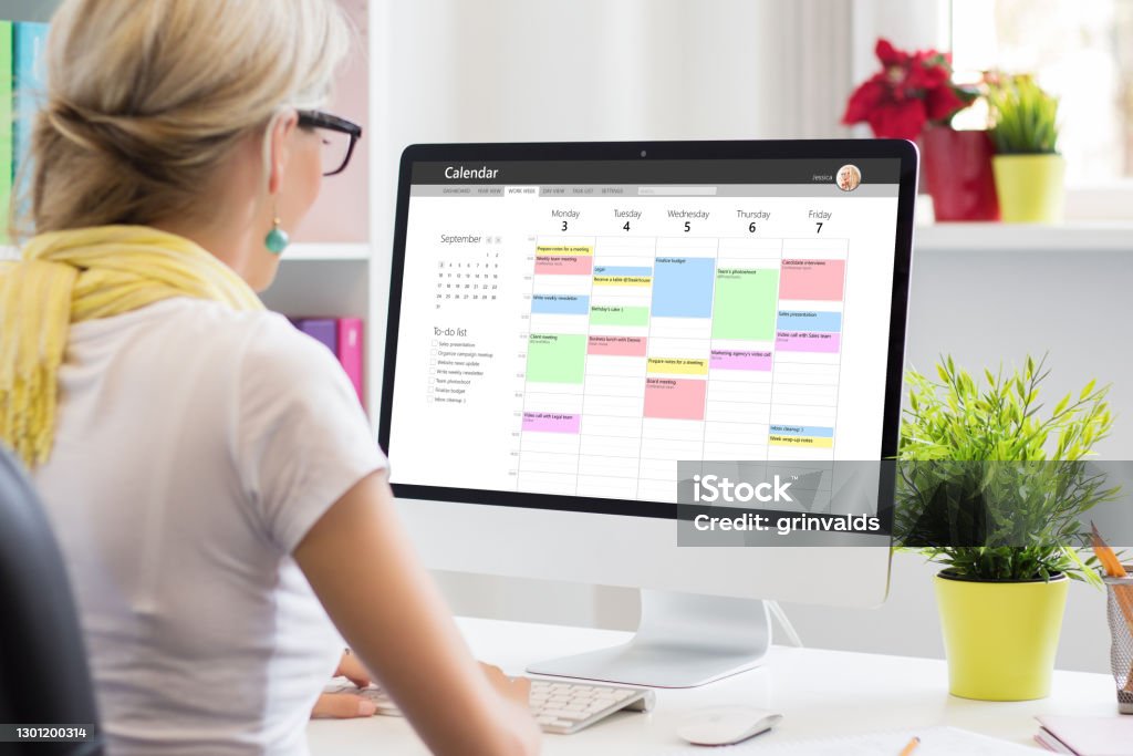Woman using calendar app on computer in office Personal Organizer Stock Photo