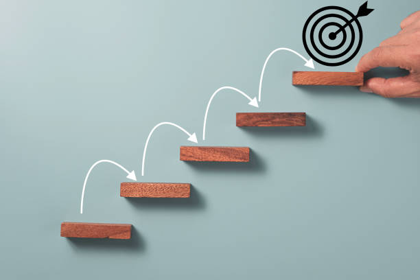 istock Hand putting block cube on target board and white arrow jumping step , achievement objective target concept. 1301200404