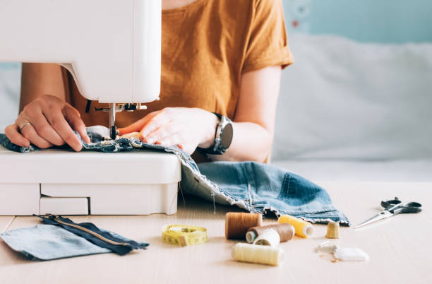 un tailleur de femme travaille à coudre la machine à coudre réutilise le tissu des vieux vêtements en denim - stitch photos et images de collection