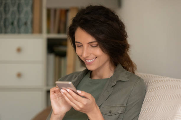 istock Smiling woman use cellphone browsing internet at home 1301207894