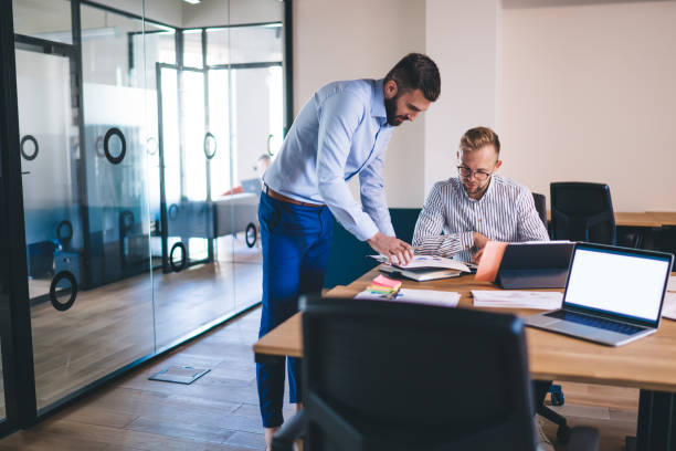 istock Skilled 20s male millennials colleagues discussing report and planning for startup projects at meeting in coworking office, man employee having conversation with boss consulting about strategy 1301209790