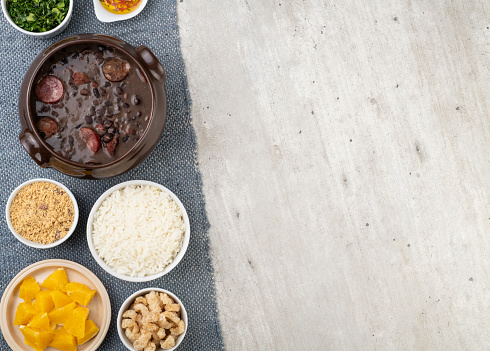 Traditional brazilian feijoada with rice, kale, orange, cracklings, manioc flour and copy space.