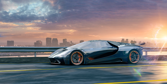 A generic dark blue grey electric sports car with rims containing built in lights. The vehicle is driving at speed on a road with yellow lane markings and a view across water to a cityscape of tall buildings under a bright dawn sky with low bright sun.