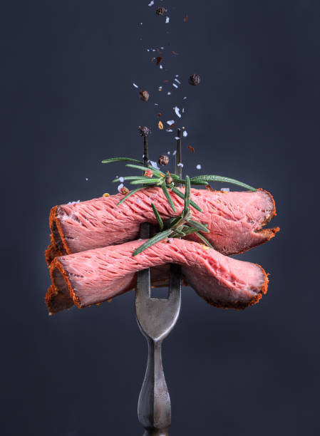 Peppered roast beef pastrami slices folded big fork and sprinkled with salt and pepper.