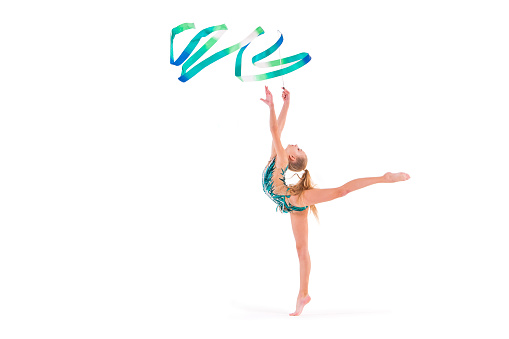 gymnast girl in an emerald swimsuit performs an exercise with a ribbon isolated on a white background