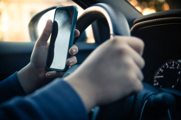 les adolescents conduisent une voiture et utilisent un smartphone. jeune homme affichant des messages retenant un téléphone portable tout en conduisant. comportement dangereux, risque d’accident. danger, transgression, jeunesse, concept de distraction. - driving text messaging accident car photos et images de collection