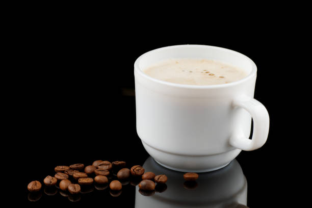 istock Cappuccino in a cup and coffee beans on a black background 1301225689
