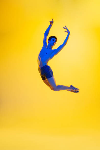 istock Young and graceful ballet dancer isolated on yellow studio background in neon light. Art, motion, action, flexibility, inspiration concept. 1301228785
