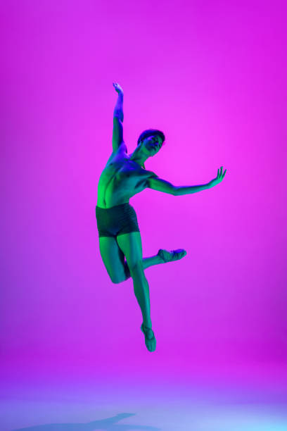 istock Young and graceful ballet dancer isolated on purple studio background in neon light. Art, motion, action, flexibility, inspiration concept. 1301228831