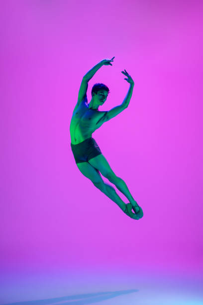 istock Young and graceful ballet dancer isolated on purple studio background in neon light. Art, motion, action, flexibility, inspiration concept. 1301228832