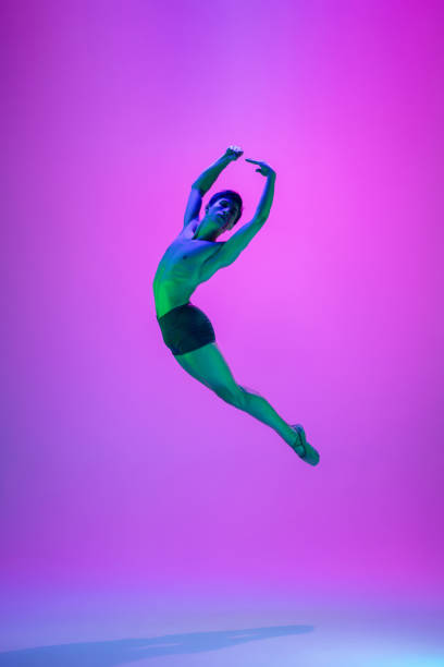 istock Young and graceful ballet dancer isolated on purple studio background in neon light. Art, motion, action, flexibility, inspiration concept. 1301228839