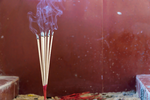 Close-up of burning incense sticks with smoke in the Buddhist temple.