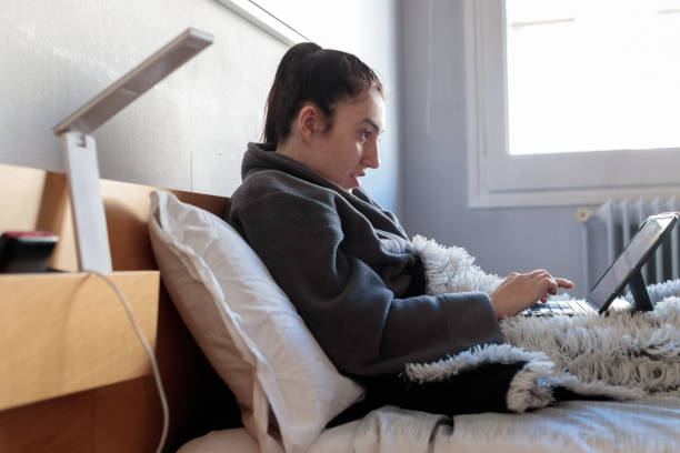istock Young woman writing with her tablet in bed 1301229878