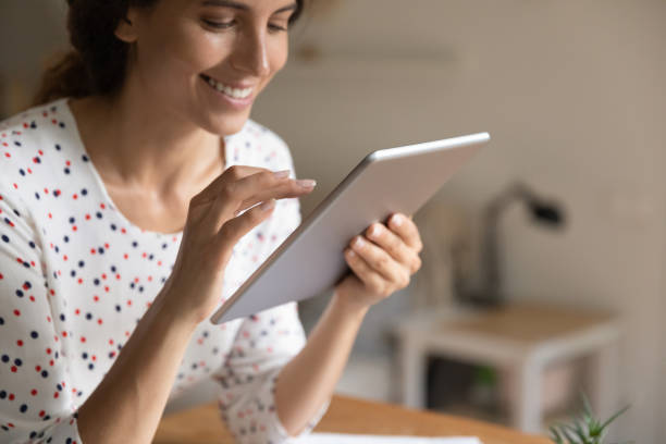 istock Smiling woman look at table screen browsing internet 1301230346