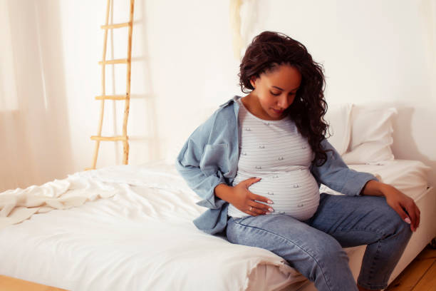 młoda dość afroamerykańska kobieta w ciąży r. w łóżku, koncepcja ludzi stylu życia - one person women human pregnancy beautiful zdjęcia i obrazy z banku zdjęć