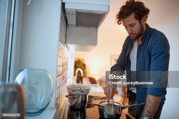 Young Man Preparing A Meal On A Stove In The Kitchen Kitchen Housework Quarantin Home Stock Photo - Download Image Now