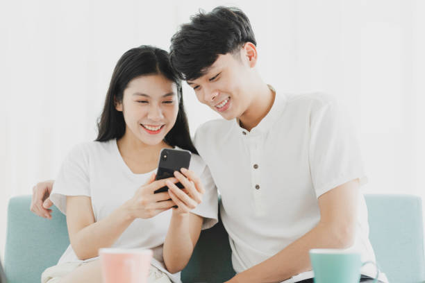 Young couple Young couple looking at the phone together with happy expression happy filipino family stock pictures, royalty-free photos & images