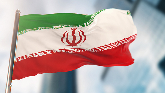 National Flag of Iran Against Defocused City Buildings