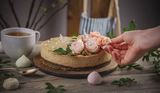 istock Decorator's hand is decorating the delicious raw mousse cake with tenderness pink flowers. Concept of romantic mood and spring atmosphere 1301239015