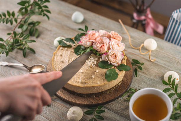 istock Woman's hand is cutting a beautiful raw mousse cake decorated with tenderness flowers. Concept of a romantic atmosphere and spring mood 1301239021