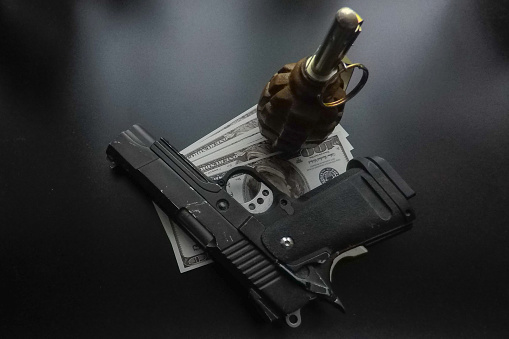 the black background a pistol and a hand grenade