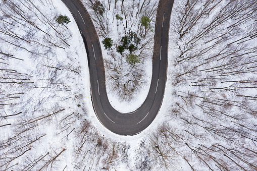 aerial curve of country road in snow covered forest from above