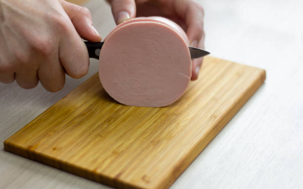 Slice the sausage.Men's hands are slicing sausage.