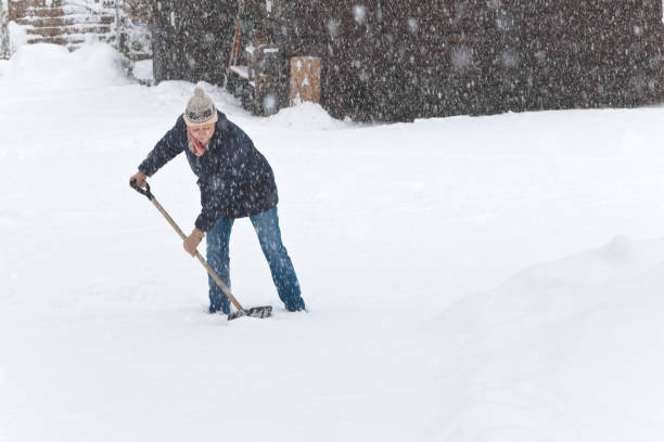 istock Woman shoveling snow in heavy snowfall 1301241681