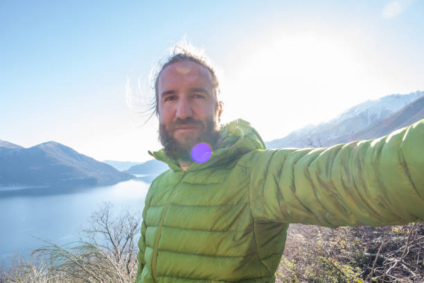 istock Man taking a selfie on a hike with mountains and lake view 1301241711