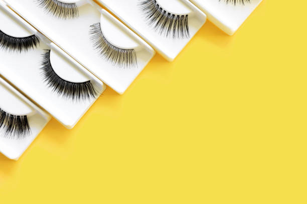 istock Different fake eyelashes on trendy bright yellow background. Beauty pattern. Makeup accessories. Cosmetics products for women. Top view, flat lay. Copy space. Place for text. Illuminating banner. 1301242976