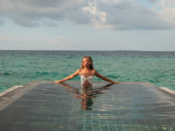 istock Beautiful woman enjoys sunset from infinity pool over reef 1301243464