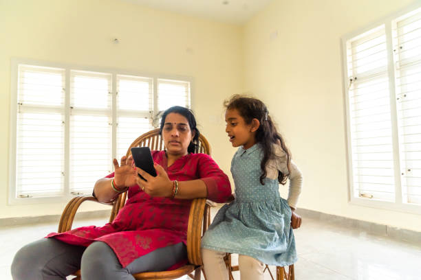 madre e figlia guardando il cellulare a casa - mobile phone photography bangalore offspring foto e immagini stock