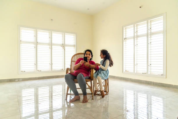 madre e figlia guardando il cellulare a casa - mobile phone photography bangalore offspring foto e immagini stock
