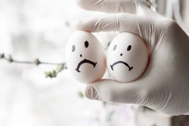 Urology concept. Male problems, infertility, decreased testosterone. Chicken eggs in hand with sad emoticons.