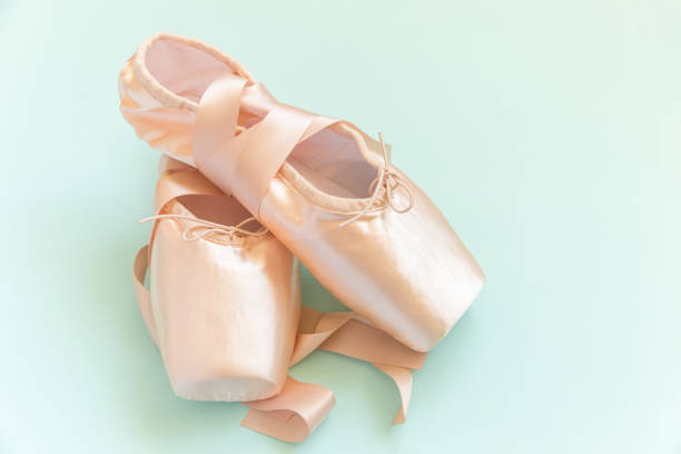 New pastel beige ballet shoes with satin ribbon isolated on blue background. Ballerina classical pointe shoes for dance training. Ballet school concept. Top view flat lay, copy space New pastel beige ballet shoes with satin ribbon isolated on blue background. Ballerina classical pointe shoes for dance training. Ballet school concept. Top view flat lay copy space ballerina shoes stock pictures, royalty-free photos & images