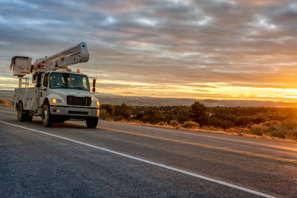 ein eimer oder eine luftplattform, boom truck fahren durch die wüste von utah, in der nähe von moab, wilson arch, mit einem dramatischen sonnenuntergang nach westen - eimer stock-fotos und bilder