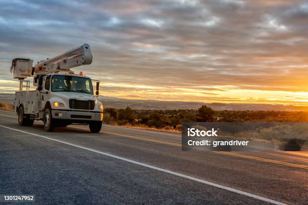 A Bucket Or Aerial Platform Boom Truck Driving Through The Desert Of Utah Near Moab Wilson Arch With A Dramatic Sunset To The West Stock Photo - Download Image Now