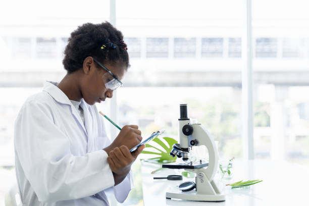 istock African American girl scientists learning and writing science and doing analysis for germs and bacteria with microscope in the laboratory. Science and education, researcher and discovery concept 1301248923